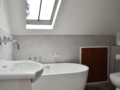 bagno con vasca, lavandino e lucernario. di Tanners Cottage a Cockermouth