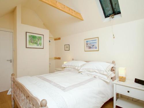 a bedroom with a large white bed with white pillows at Tullibole Castle Longhouse in Crook of Devon