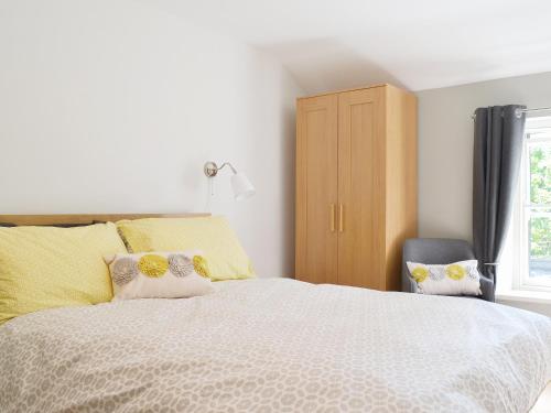 Un dormitorio con una cama con almohadas amarillas y una silla en Clarence Cottage, en Appleby