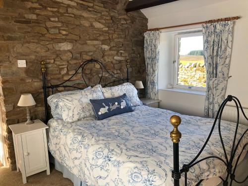 a bedroom with a bed and a stone wall at Borrowdale Cottage in Brough