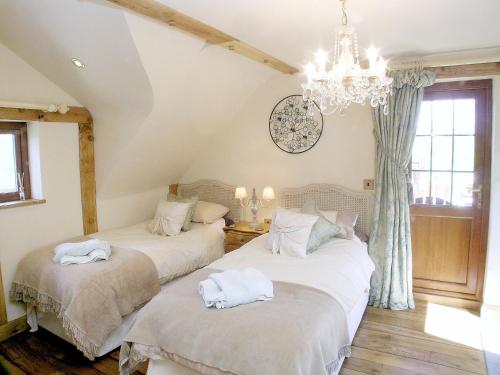 two beds in a room with a chandelier at The Old Stables in Crynant