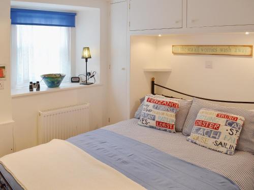 a bedroom with a bed with pillows and a window at Driftwood in St Ives