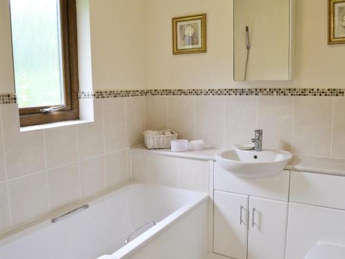a white bathroom with a tub and a sink at Moorland Lodge in Chalbury