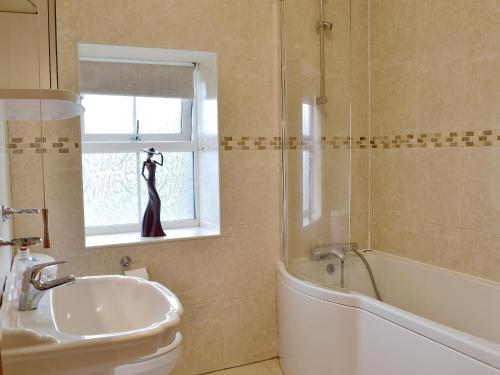 a bathroom with a sink and a tub and a window at 5 Pengraig Draw in Llanychaiarn