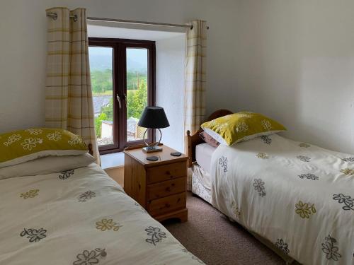 two beds in a room with a window at Rock Cottage in Crosthwaite