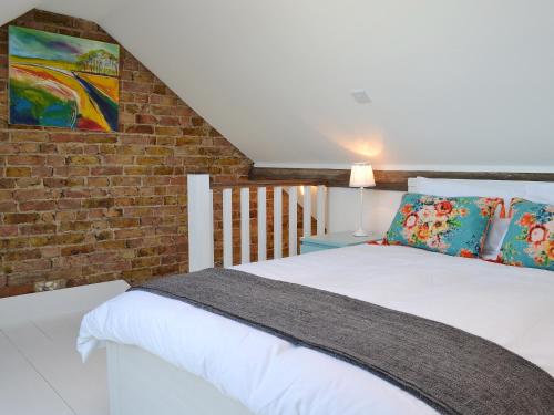 a bedroom with a white bed and a brick wall at Coastguard Cottage in Chestfield