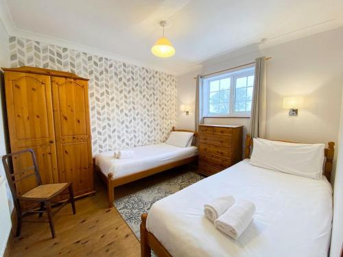 a bedroom with two beds and a chair and a window at Sweet Coppin in Ledbury