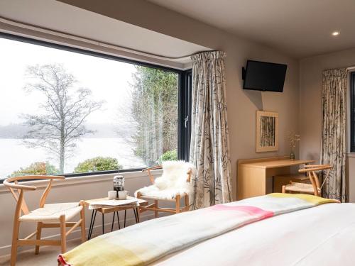 1 dormitorio con cama y ventana grande en Carsaig, en Port of Menteith