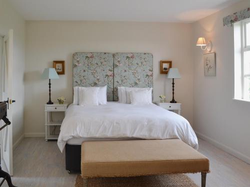 een slaapkamer met een groot wit bed met een bloemrijk hoofdeinde bij Snooty Fox Cottage in Hexham