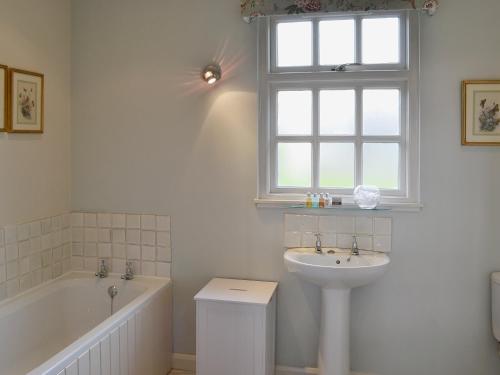 a bathroom with a sink and a bath tub and a window at Snooty Fox Cottage in Hexham