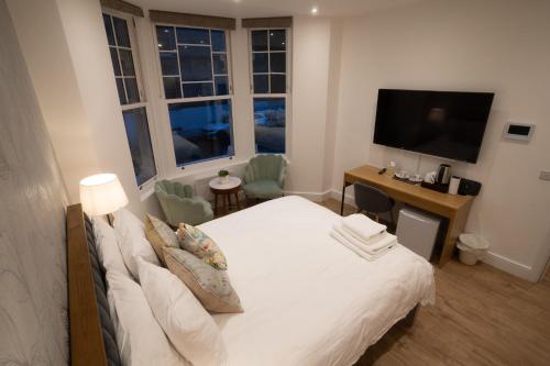 a bedroom with a white bed and a television at The Avonmore Olympia in London