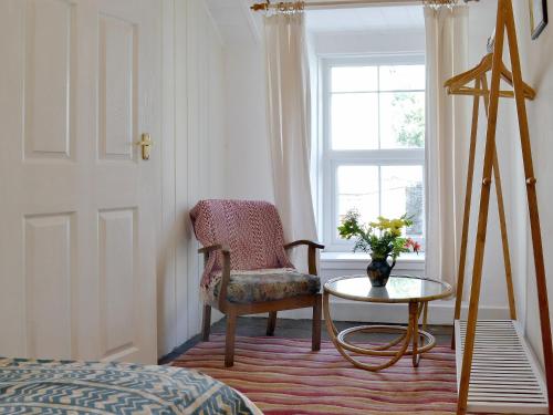 a bedroom with a chair and a table and a window at Gerlan in Tregaron