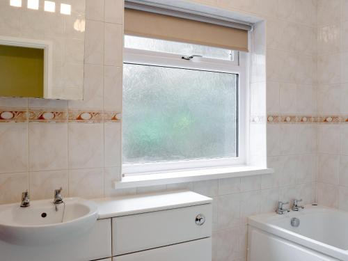 a white bathroom with a sink and a window at Ty Howton in Clydach