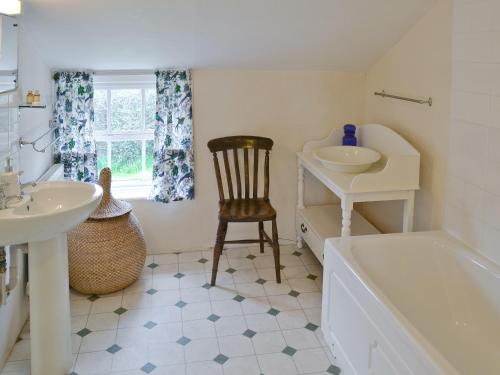 a bathroom with a sink and a tub and a chair at Varley House in Saxmundham