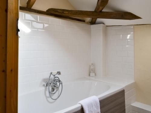 uma banheira branca na casa de banho com tecto em madeira em The Cart Lodge-e3568 em Uggeshall