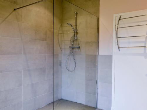 a bathroom with a shower with a glass door at Perch Hall Cottage in Dinwoodie Mains