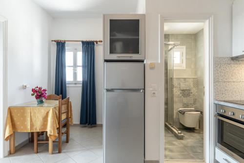 a kitchen with a table and a refrigerator with a microwave at Crystal Naxos 1 Studios at Mikri Vigla in Mikri Vigla
