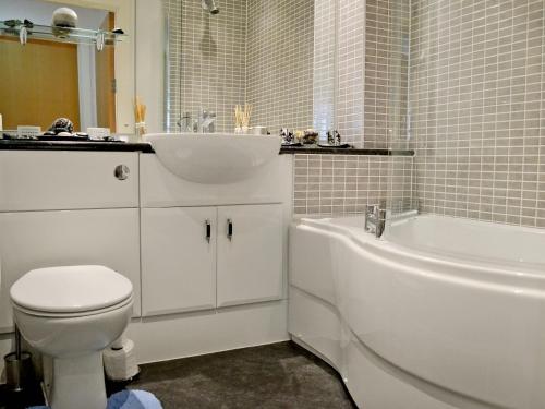 a bathroom with a toilet and a sink and a bath tub at Waters Edge in Llanelli
