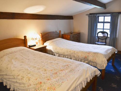 a bedroom with two beds and a window at High Windy Cottage in Garrigill