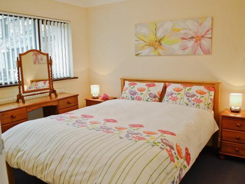 a bedroom with a bed and a dresser and a mirror at Riverside in Carlyon Bay