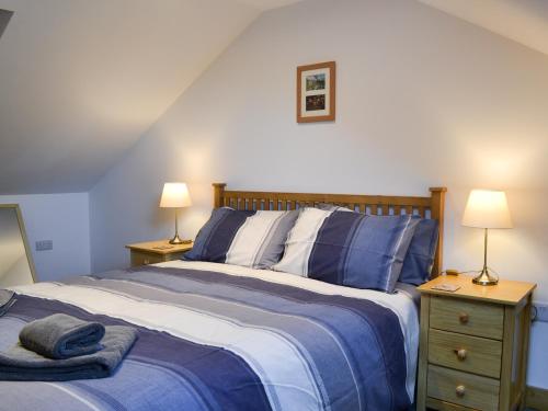 a bedroom with a bed with blue sheets and two lamps at The Granary in Criccieth