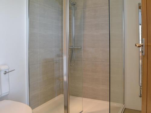 a shower with a glass door in a bathroom at The Granary in Criccieth