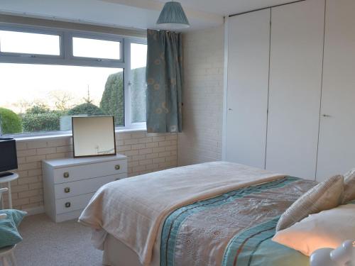 a bedroom with a bed and a tv and a window at The Lookout in Torquay