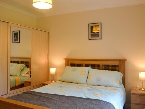 a bedroom with a bed with two lamps and a mirror at Cameron Lodge Cottage in Innellan