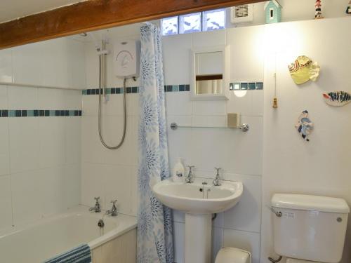 uma casa de banho com um lavatório, um WC e um chuveiro em Chy An Ky Bras em Porthallow