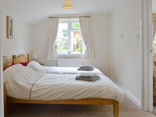 a bedroom with a bed with white sheets and a window at Little Orchard in Dursley