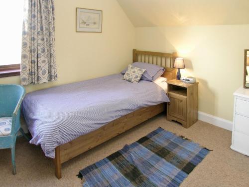 a bedroom with a bed and a table and a chair at Bramble Cottage in Meigle