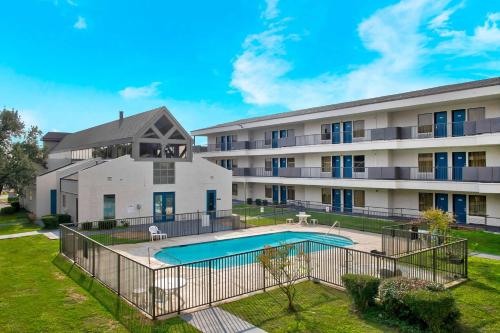 an apartment building with a swimming pool in front of it at Studio 6-San Antonio, TX - Airport in San Antonio