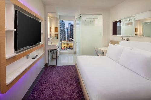 una camera d'albergo con un grande letto e una TV di YOTEL New York Times Square a New York