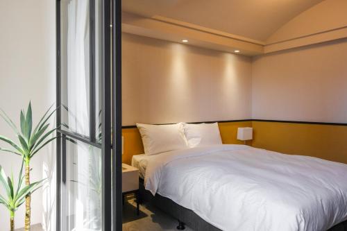 a bedroom with a white bed and a window at Giant Rich Hotel in Taipei