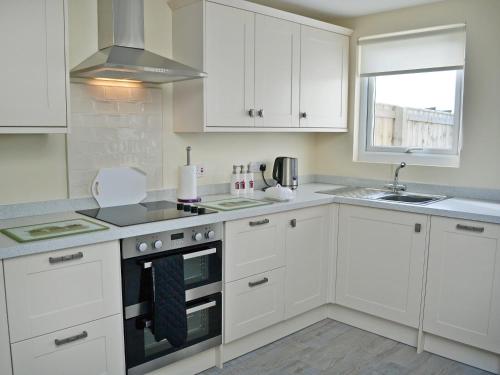 a white kitchen with white cabinets and a sink at Wayside in Beadnell