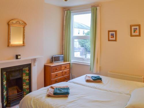 two beds in a bedroom with a fireplace and a window at Dorothy's Cottage in Torquay