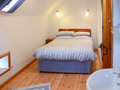 a small bedroom with a bed and a sink at Mill Cottage in John O Groats