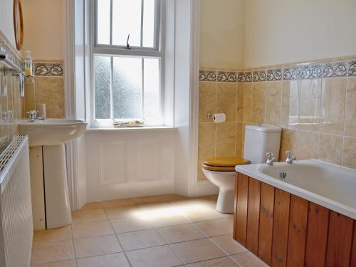 a bathroom with a tub and a toilet and a sink at Flaxmans in Parkham