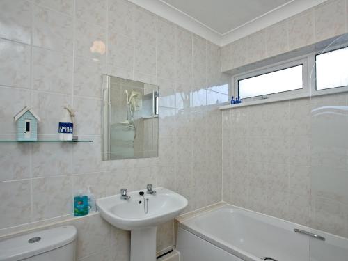 La salle de bains est pourvue d'un lavabo, d'une baignoire et de toilettes. dans l'établissement Turnstone - 2 Linden Court, à Brixham