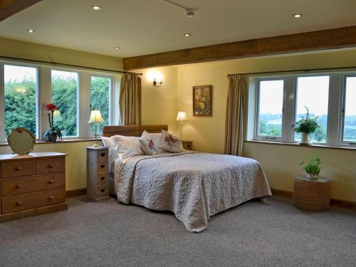a bedroom with a large bed with windows at Thurst House Farm Holiday Cottage in Ripponden