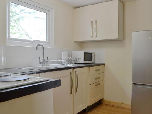 a kitchen with white cabinets and a sink and a window at Snow Whites House - Uk11479 in Felindre