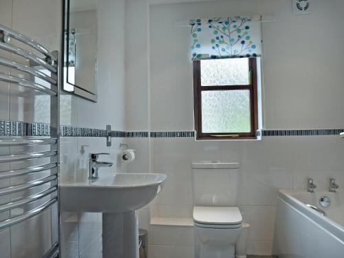 baño con lavabo y aseo y ventana en Acorn Cottage en Braithwaite