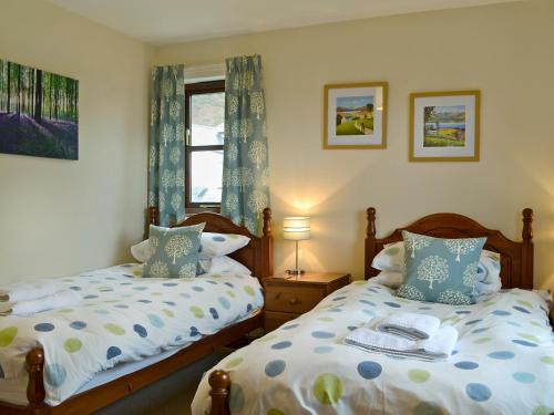 1 dormitorio con 2 camas y ventana en Acorn Cottage en Braithwaite