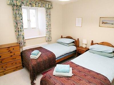 a bedroom with two beds and a window at Aira Cottage in Watermillock