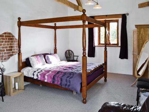 a bedroom with a wooden canopy bed with purple sheets at The Place 2b in Tresmeer