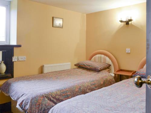 1 dormitorio con 2 camas y una cruz en la pared en Chaffcuttters, en East Down