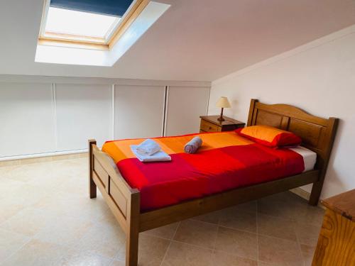 una camera da letto con un letto con lenzuola rosse e una finestra di SwordFish Beach Apartment a Peniche