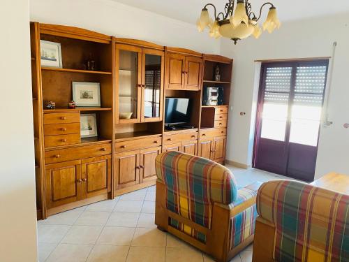 ein Wohnzimmer mit einem TV, einem Sofa und einem Stuhl in der Unterkunft SwordFish Beach Apartment in Peniche