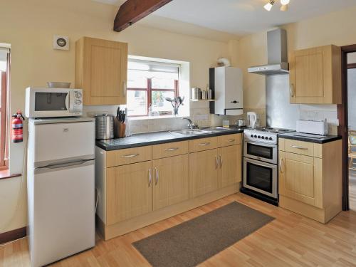 a kitchen with wooden cabinets and a white refrigerator at Swallow Cottage in Ferryhill