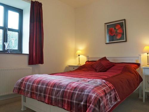 a bedroom with a bed with a red blanket and a window at Swallow Cottage in Ferryhill